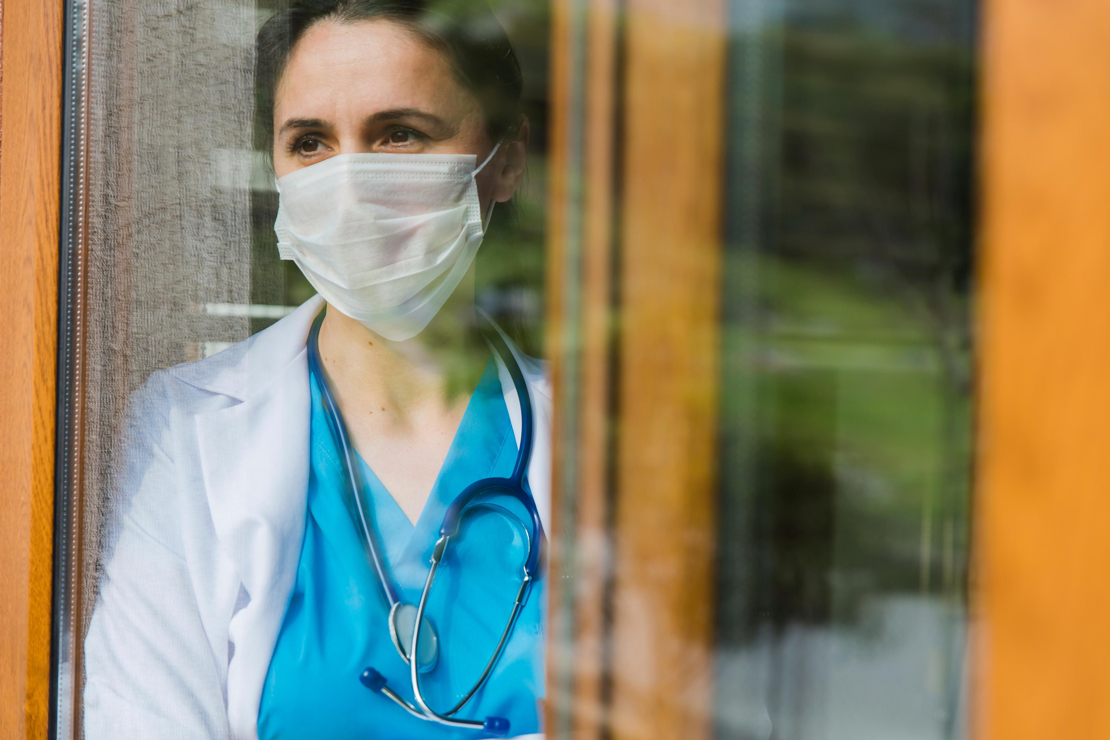 Female doctor looking through window at hospital